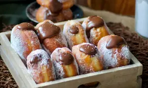 Un plateau en bois rempli de beignets au chocolat, saupoudrés de sucre glace. Un délice gourmand !