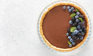 Une délicieuse tarte au chocolat au lait, garnie de myrtilles et de mûres fraîches, prête à être dégustée.