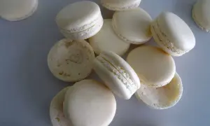 Des macarons blancs, certains assemblés, d'autres séparés, prêts pour la cuisson macaron chaleur tournante.