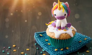 Un cupcake orné d'un adorable licorne en pâte à sucre, posé sur un glaçage blanc et des étoiles dorées. Le glaçage cupcake sucre glace est parfait pour une touche magique.