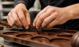 Mains habiles plaçant un chocolat décoratif dans un moule en silicone pour faire des chocolats.