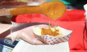 Une cuillère en bois verse du caramel coulant sur des tranches de pomme dans un petit bol. Le caramel est fait avec du sucre, quel sucre pour faire du caramel ?