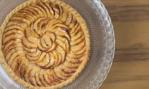 Tarte aux pommes recette : une tarte aux pommes dorée, disposée en spirale sur un plat en verre, prête à être dégustée.