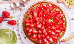 Tarte fraise pistache, une gourmandise aux couleurs vives, garnie de fraises fraîches et de pistaches concassées sur une crème onctueuse.