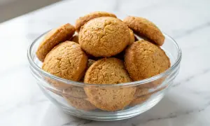 Un bol en verre rempli de petits biscuits dorés, parfaits pour une recette facile.