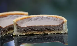 Tarte chocolat praliné croustillant, une tranche révèle sa texture onctueuse et sa base dorée.