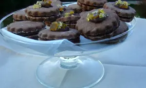 Gourmandes bouchées de biscuits fourrés chocolat, ornées de zestes d'agrumes confits, présentées dans une coupe en verre.