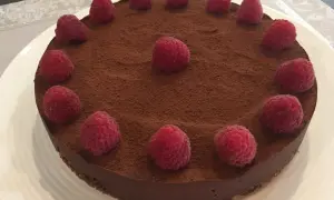 Tarte chocolat framboise, une gourmandise visuellement irrésistible, saupoudrée de cacao et ornée de framboises fraîches.