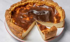 Une délicieuse tarte au flan, dorée et légèrement caramélisée, avec une part coupée pour révéler sa texture crémeuse.