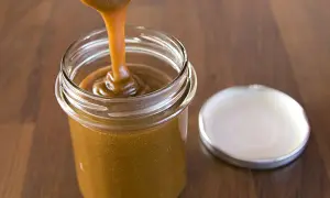 Caramel coulant versé dans un pot en verre, parfait pour une recette de pâte à tartiner noisettes maison.