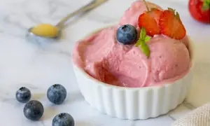 Délicieuse glace au yaourt maison aux fraises et myrtilles, garnie de fruits frais.