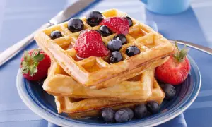 Pile de gaufres dorées garnies de fraises et myrtilles, un délice pour la meilleure recette de gaufres.
