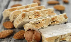 Délicieux nougat Montélimar recette, avec amandes et noisettes sur fond de bois.