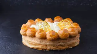 Un magnifique gâteau Saint-Honoré, avec ses choux caramélisés et sa crème aérienne, prêt à être dégusté.