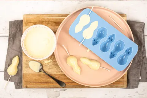 Préparation de **chocolat blanc** pour des souris en moule. Un bol de chocolat fondu, une cuillère, et des formes de souris en cours de fabrication.