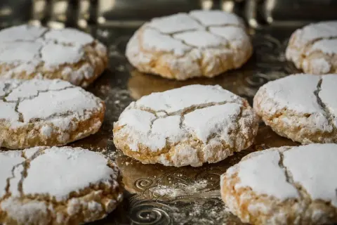 Biscuits craquelés saupoudrés de sucre glace, parfaits pour accompagner votre café. Recette facile pour faire de la poudre d'amande maison.