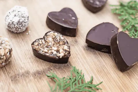 Chocolats maison en forme de cœur, certains garnis de noix, parfaits pour une recette petit chocolat maison facile.