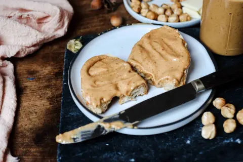 Tranches de pain généreusement tartinées d'une onctueuse pâte à tartiner chocolat blanc noisette, prêtes à être dégustées.