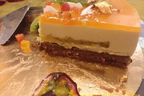 Tranche de gâteau mousseux à l'orange et au fruit de la passion, garnie de fruits et de kiwi.