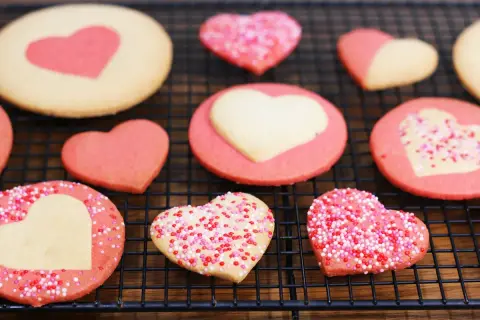 Délicieux cookies maison en forme de cœur, certains décorés de vermicelles colorés. Parfait pour apprendre comment faire des cookies maison.