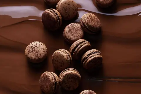 Douceurs chocolatées pour une recette macaron chocolat parfaite. Ces macarons aux éclats de cacao reposent sur un lit de chocolat fondant.