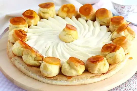 Un magnifique gâteau Saint-Honoré, orné de choux caramélisés et d'une crème onctueuse, prêt à être dégusté.