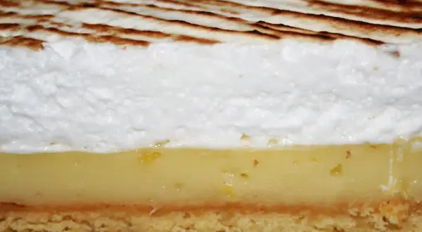 Tranche de tarte au citron avec une généreuse couche de meringue italienne dorée.