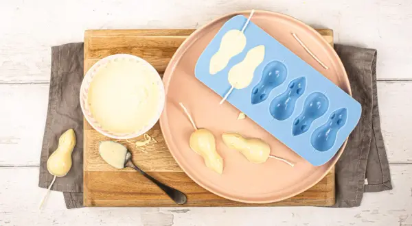 Préparation de **chocolat blanc** pour des souris en moule. Un bol de chocolat fondu, une cuillère, et des formes de souris en cours de fabrication.