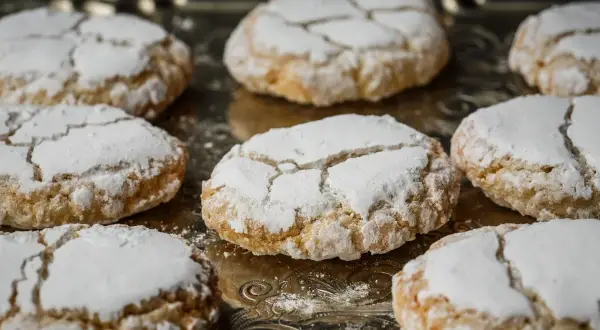 Biscuits craquelés saupoudrés de sucre glace, parfaits pour accompagner votre café. Recette facile pour faire de la poudre d'amande maison.