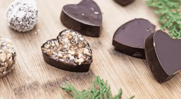 Chocolats maison en forme de cœur, certains garnis de noix, parfaits pour une recette petit chocolat maison facile.
