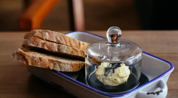 Tranches de pain artisanal avec une portion de beurre aux herbes, une excellente alternative par quoi remplacer le beurre.