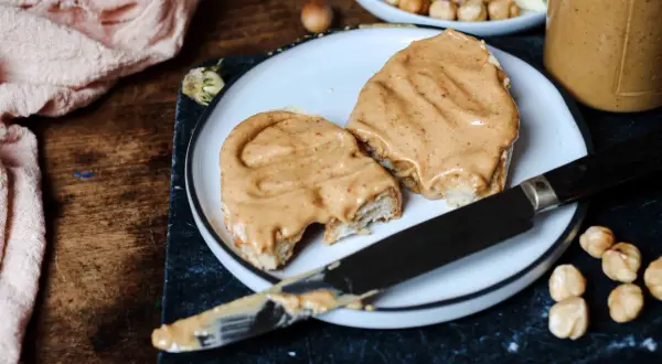 Tranches de pain généreusement tartinées d'une onctueuse pâte à tartiner chocolat blanc noisette, prêtes à être dégustées.