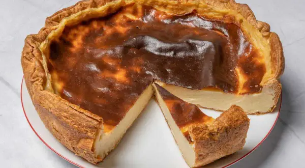 Une délicieuse tarte au flan, dorée et légèrement caramélisée, avec une part coupée pour révéler sa texture crémeuse.