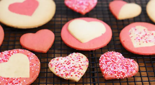 Délicieux cookies maison en forme de cœur, certains décorés de vermicelles colorés. Parfait pour apprendre comment faire des cookies maison.
