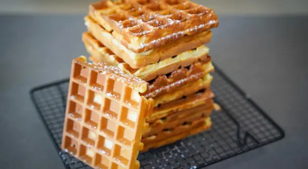 Pile de gaufres dorées saupoudrées de sucre glace, parfaites pour une recette gaufre levure chimique.