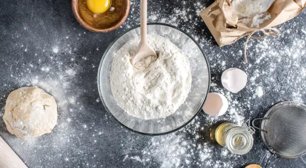 Préparation d'une recette avec de la farine T80, c'est quoi ? Œuf, pâte, lait, huile, tamis, tout est prêt pour le pain.