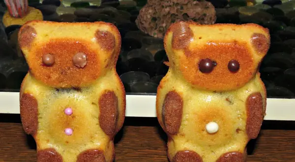 Deux oursons en gâteau, parfaits pour une recette ourson chocolat. Ils ont des yeux en chocolat et des boutons roses ou blancs.