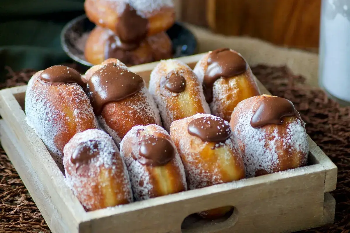 Un plateau en bois rempli de beignets au chocolat, saupoudrés de sucre glace. Un délice gourmand !