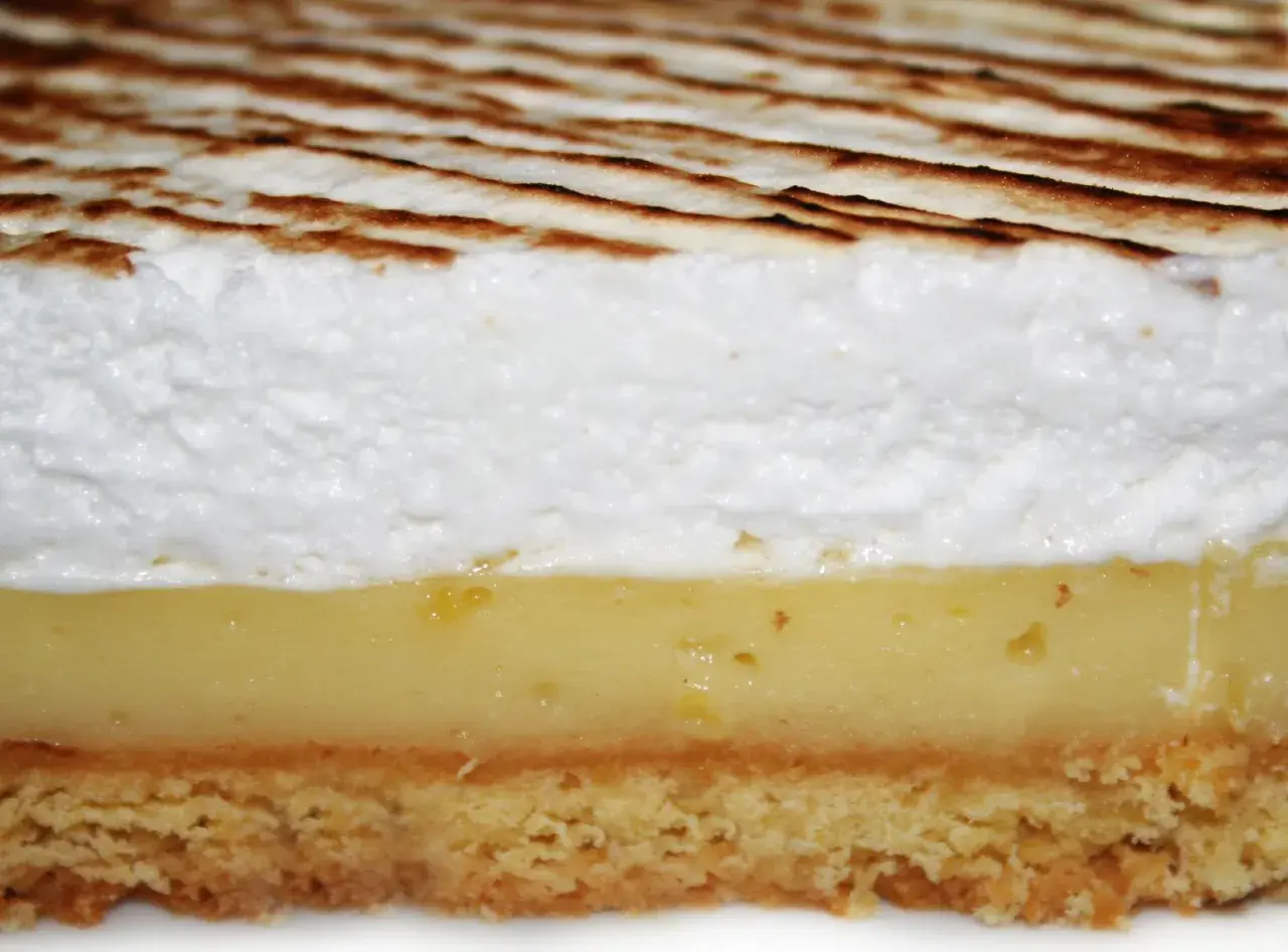 Tranche de tarte au citron avec une généreuse couche de meringue italienne dorée.