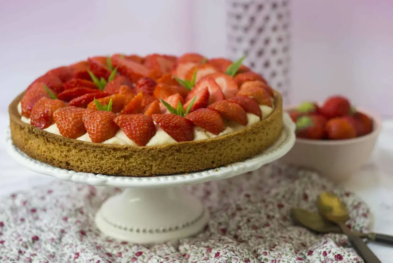 Tarte aux fraises sablé breton, garnie de crème pâtissière et de fraises fraîches, décorée de feuilles de menthe.