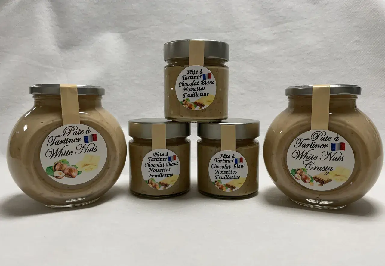 Cinq pots de pâte à tartiner "White Nuts" et "Chocolat Blanc Noisettes Feuilletine", une délicieuse recette nocciolata bianca.