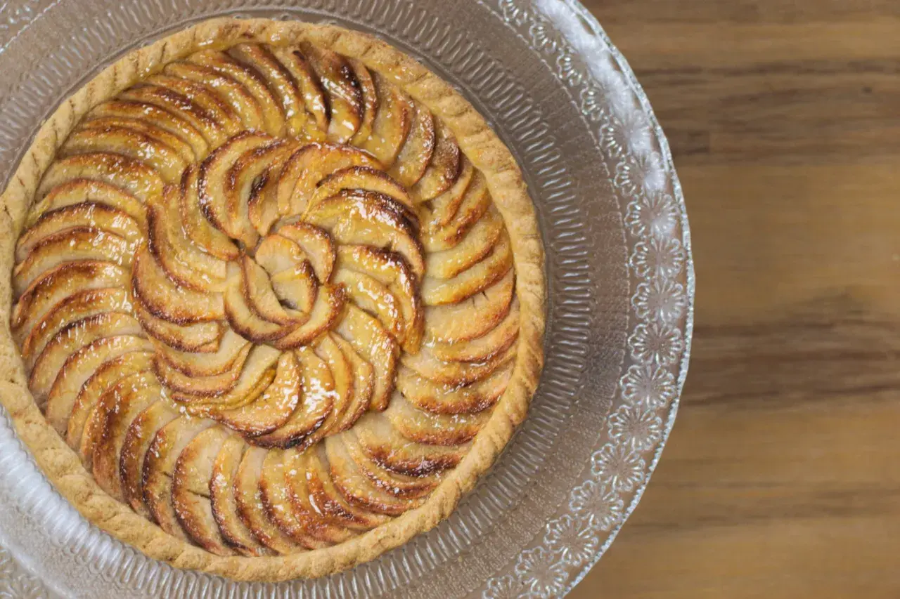 Tarte aux pommes dorée, joliment disposée en spirale. Quelle pâte pour une tarte sucrée ? Une pâte sablée croustillante serait parfaite.