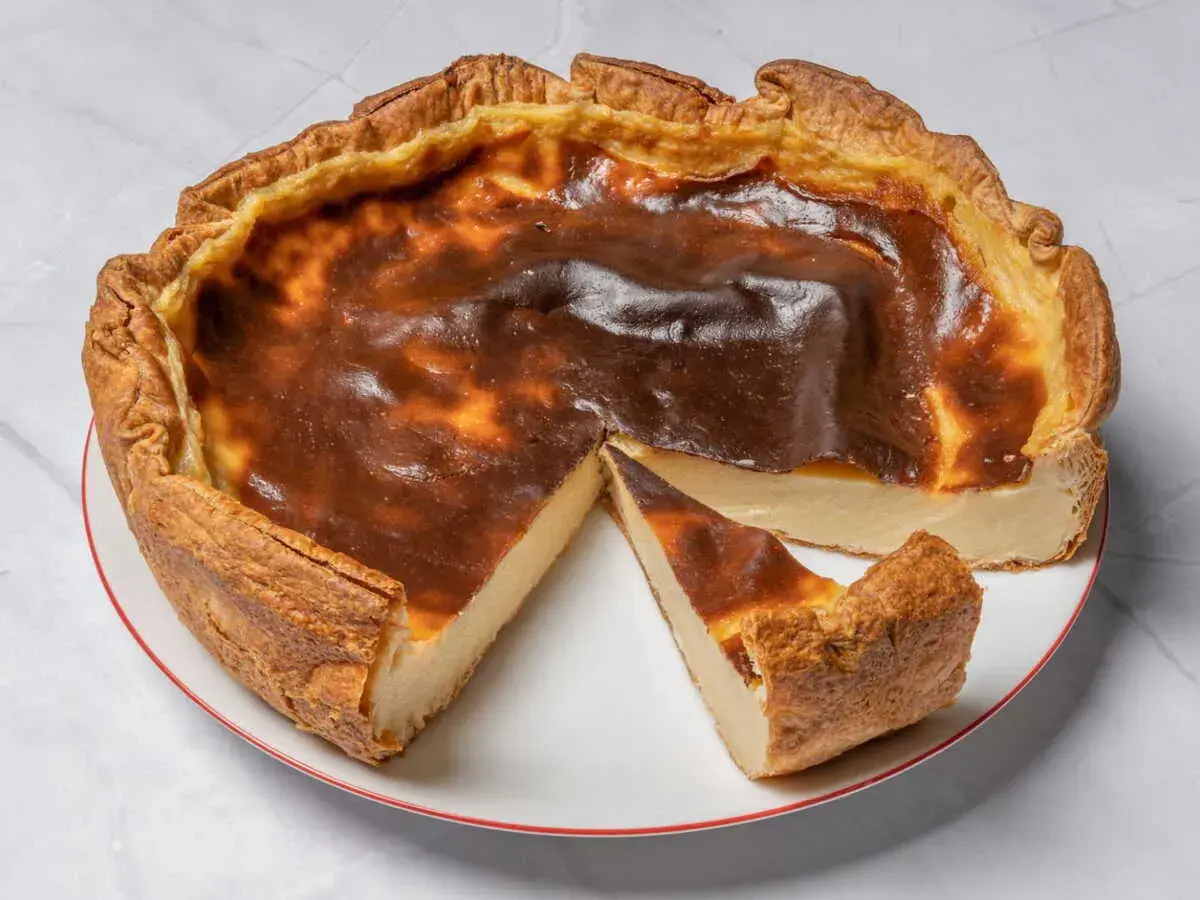 Une délicieuse tarte au flan, dorée et légèrement caramélisée, avec une part coupée pour révéler sa texture crémeuse.