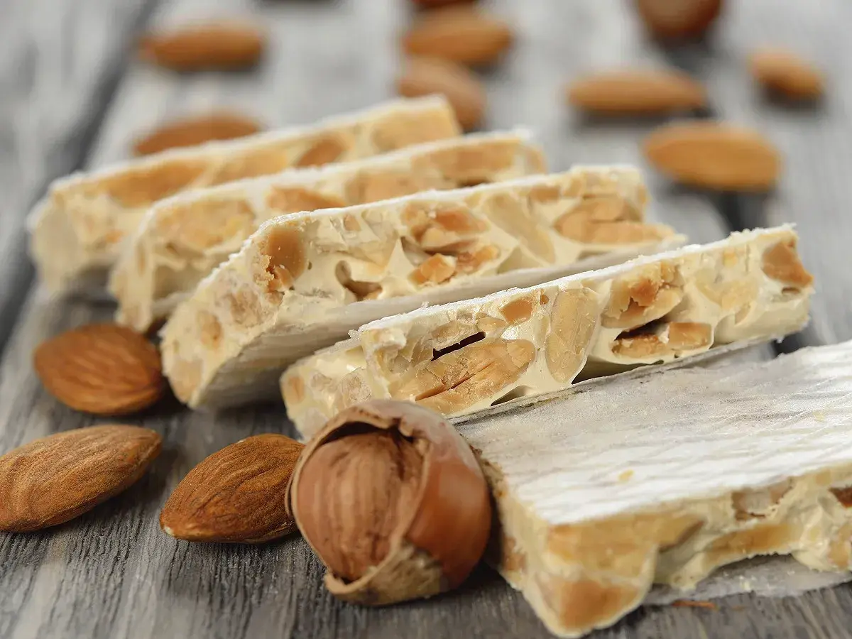 Délicieux nougat Montélimar recette, avec amandes et noisettes sur fond de bois.