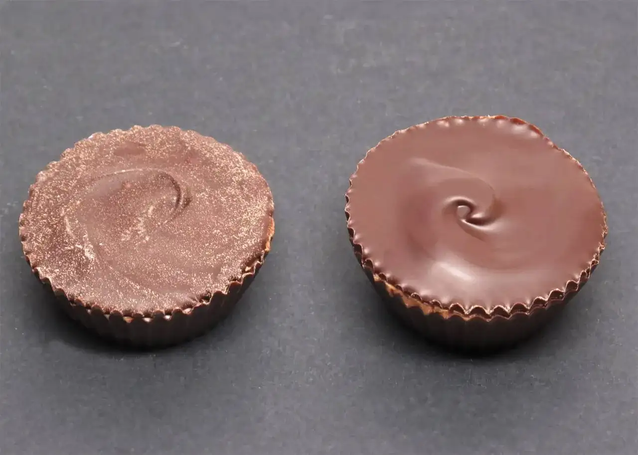 Deux bonbons au chocolat noir, l'un mat et l'autre brillant, montrant le résultat d'un bon tempérage du chocolat.