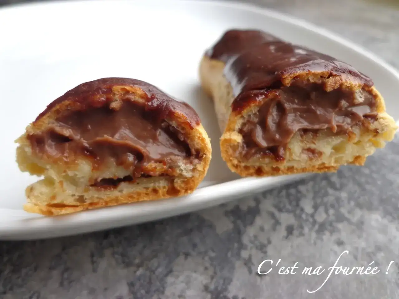 Deux éclairs au chocolat, l'un coupé en deux, révèlent une crème onctueuse. Un délice gourmand !