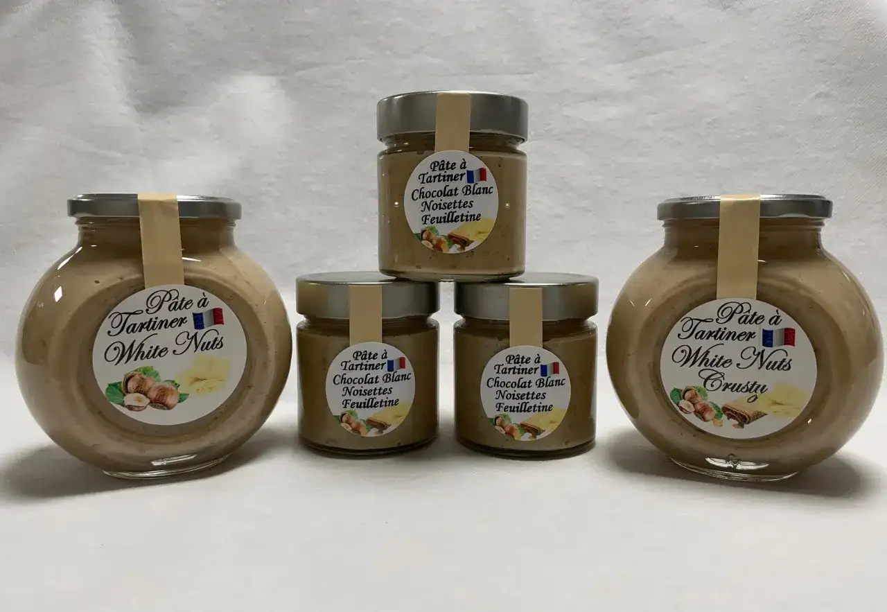 Cinq pots de pâte à tartiner "White Nuts" et "Chocolat Blanc Noisettes Feuilletine", une délicieuse recette nocciolata bianca.