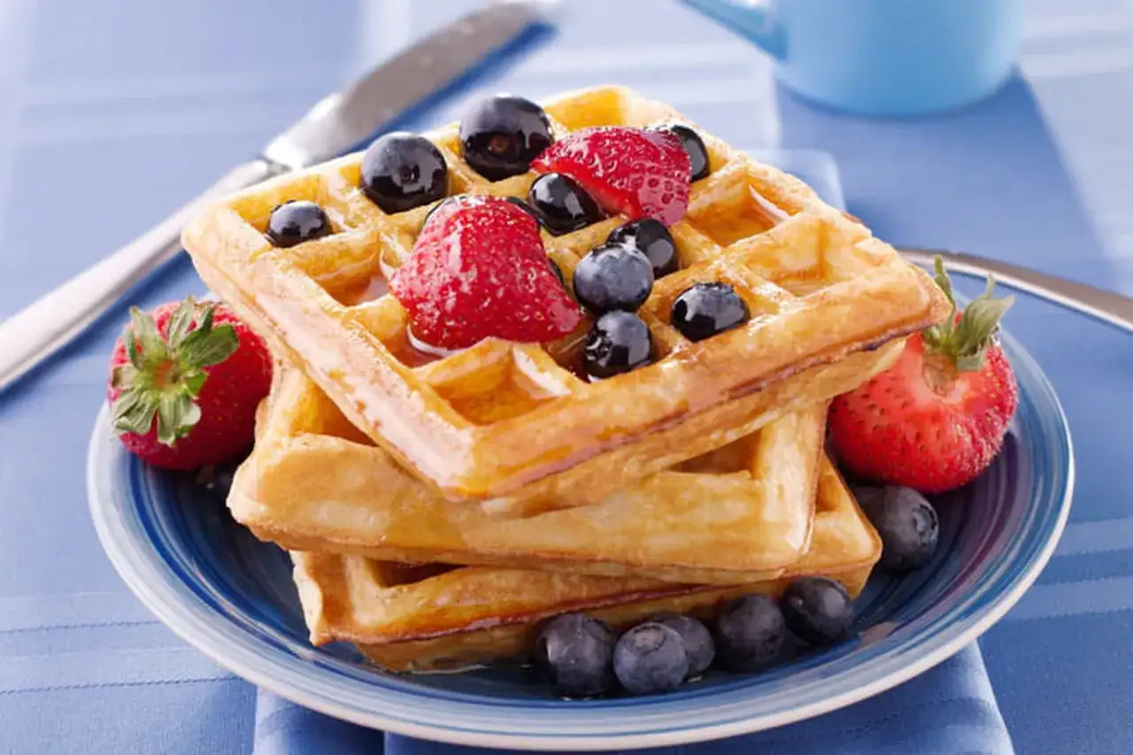 Pile de gaufres dorées garnies de fraises et myrtilles, un délice pour la meilleure recette de gaufres.