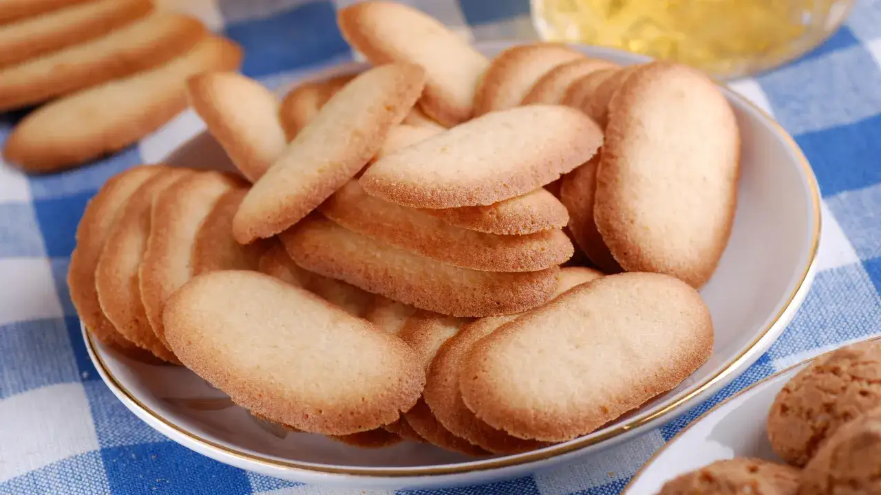 Une assiette de biscuits fins, parfaits pour une recette langue de chat. Ils sont dorés et croustillants, prêts à être dégustés.