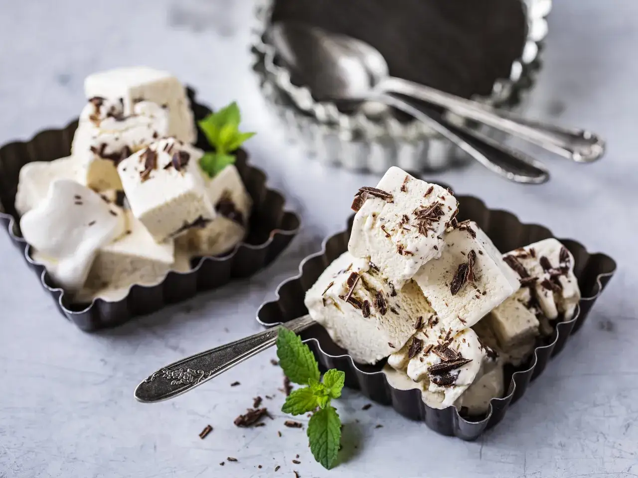 Délicieuse glace stracciatella recette, servie dans des moules en métal avec des copeaux de chocolat noir et des feuilles de menthe fraîche.